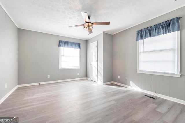 empty room featuring ceiling fan, ornamental molding, a textured ceiling, and light wood-type flooring