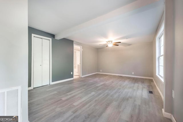 spare room featuring beamed ceiling, ceiling fan, and light hardwood / wood-style floors