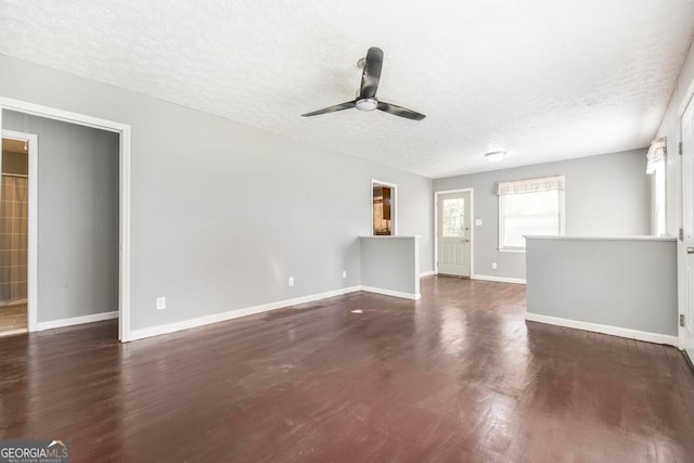 unfurnished living room featuring ceiling fan, dark hardwood / wood-style flooring, and a textured ceiling