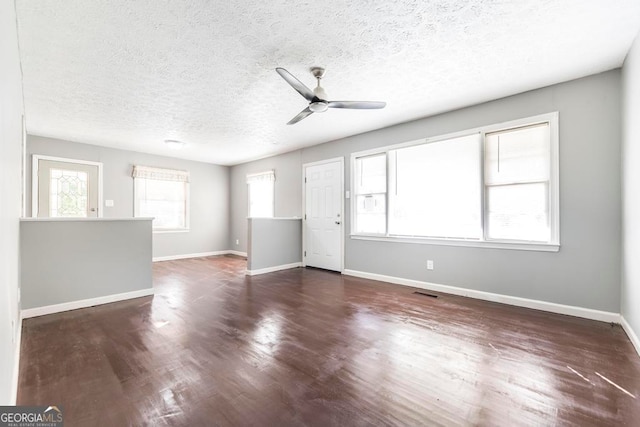 empty room with dark hardwood / wood-style flooring, plenty of natural light, and a textured ceiling