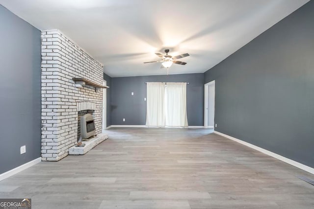 unfurnished living room featuring ceiling fan, a fireplace, and light wood-type flooring