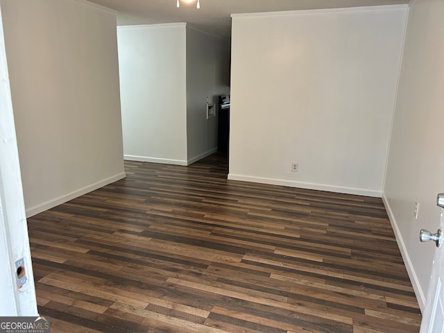 empty room with dark hardwood / wood-style flooring and crown molding