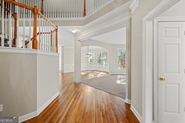 entryway with ornamental molding, hardwood / wood-style flooring, and a notable chandelier