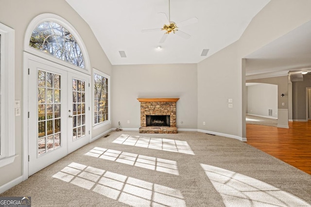 unfurnished living room with french doors, ceiling fan, light hardwood / wood-style flooring, a fireplace, and lofted ceiling