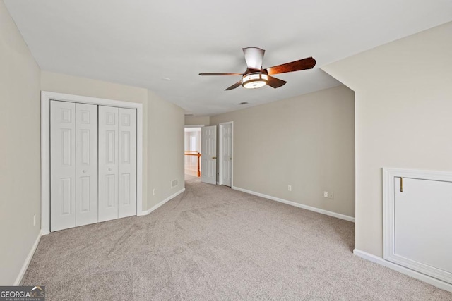 unfurnished bedroom featuring ceiling fan, a closet, and light carpet