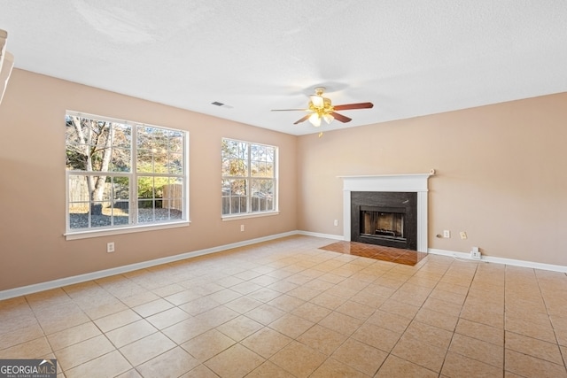 unfurnished living room with ceiling fan, light tile patterned floors, and a textured ceiling