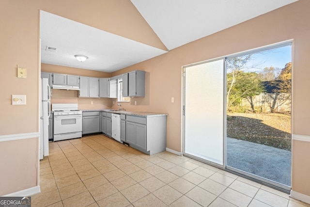 kitchen featuring lofted ceiling, white appliances, sink, gray cabinets, and light tile patterned flooring