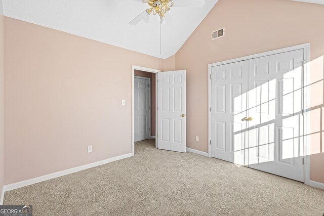 unfurnished bedroom with ceiling fan, a closet, high vaulted ceiling, and light carpet