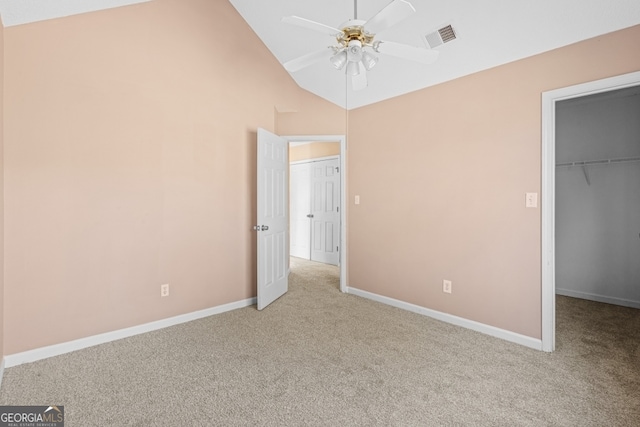 unfurnished bedroom featuring lofted ceiling, light carpet, a walk in closet, ceiling fan, and a closet