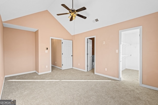 unfurnished bedroom featuring a walk in closet, a closet, ceiling fan, and light colored carpet