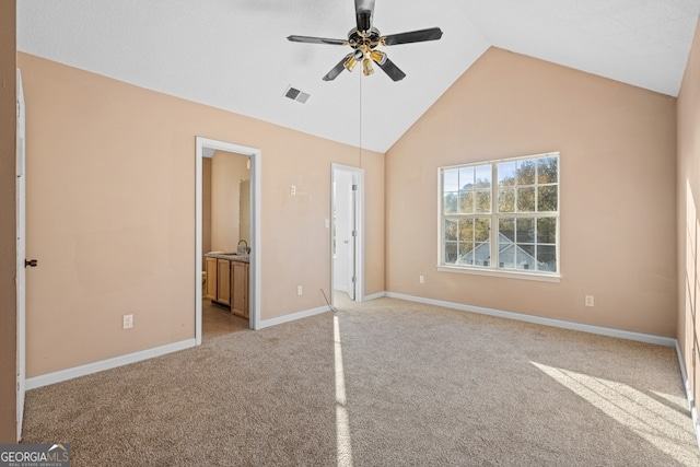 unfurnished bedroom with light carpet, connected bathroom, ceiling fan, and lofted ceiling