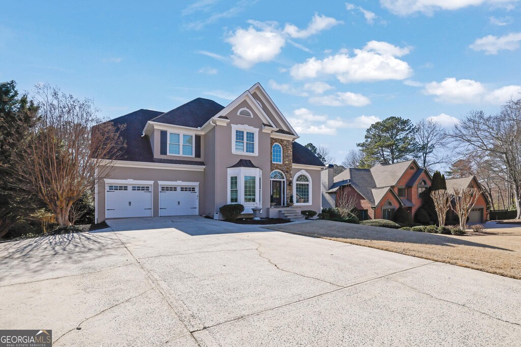 traditional-style house with a garage, driveway, and stucco siding