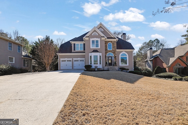 traditional-style house with an attached garage, a chimney, concrete driveway, and a front yard