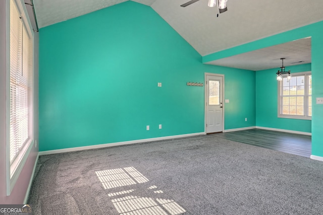 carpeted empty room featuring ceiling fan, lofted ceiling, and baseboards