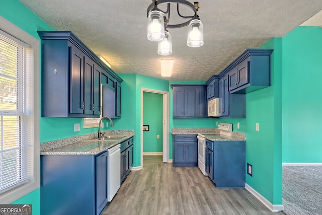 kitchen with white appliances, sink, a textured ceiling, light hardwood / wood-style floors, and light stone counters