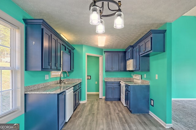 kitchen with a textured ceiling, a sink, a healthy amount of sunlight, and white appliances