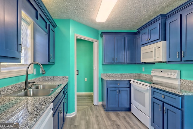 kitchen with a textured ceiling, white appliances, sink, blue cabinetry, and light hardwood / wood-style flooring