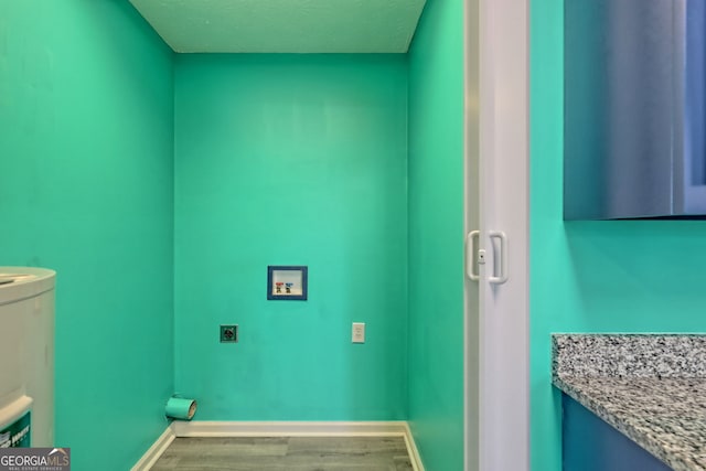 washroom with hookup for a washing machine, a textured ceiling, electric dryer hookup, water heater, and wood-type flooring