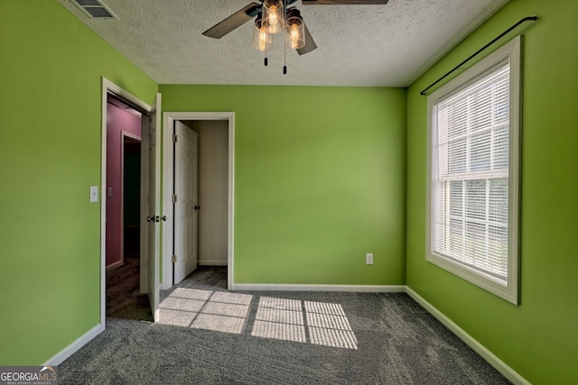 carpeted spare room with ceiling fan and a textured ceiling