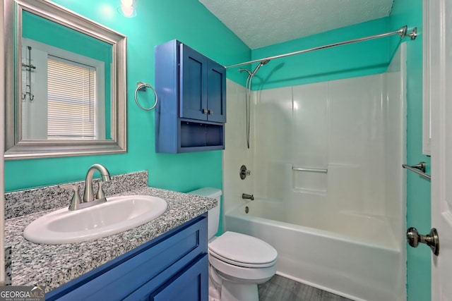 full bathroom with wood-type flooring,  shower combination, a textured ceiling, toilet, and vanity