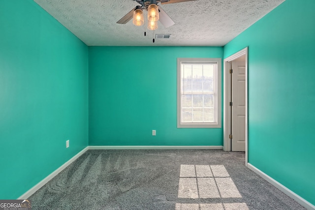 empty room featuring ceiling fan, visible vents, baseboards, a textured ceiling, and carpet floors