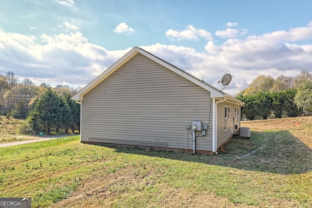 view of side of home featuring a lawn and central AC