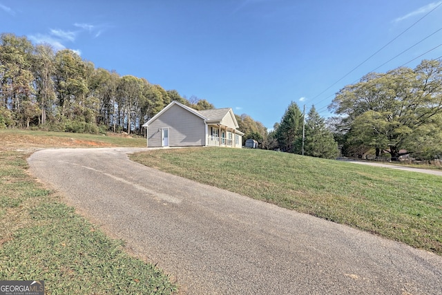 view of side of home with a yard and aphalt driveway