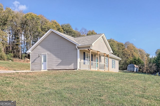 view of front of house featuring covered porch, a front yard, and a storage shed