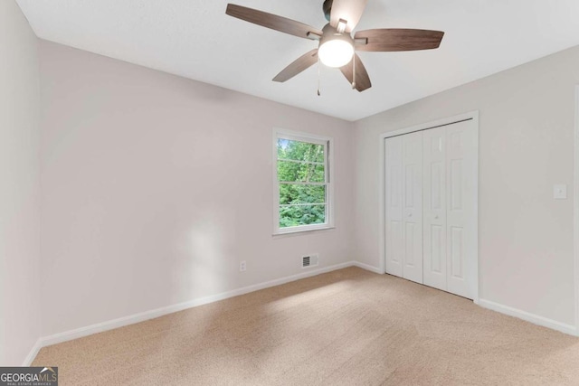 unfurnished bedroom with ceiling fan, a closet, and light carpet