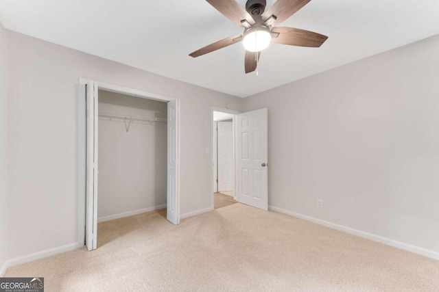 unfurnished bedroom featuring ceiling fan, a closet, and light colored carpet