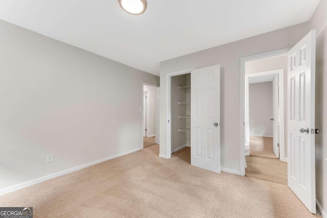 unfurnished bedroom with light colored carpet and a closet