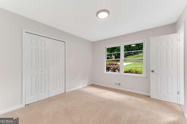 unfurnished bedroom featuring light colored carpet and a closet