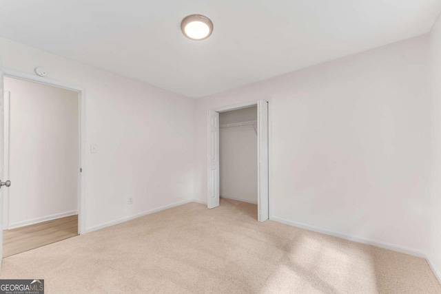 unfurnished bedroom with light colored carpet and a closet