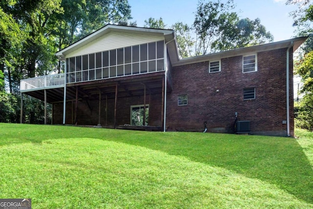 back of property with a sunroom, a deck, a lawn, and central AC