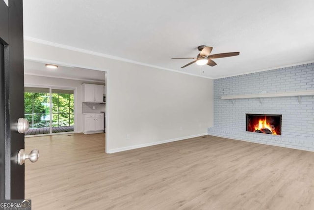 unfurnished living room with ceiling fan, light hardwood / wood-style flooring, crown molding, and a brick fireplace