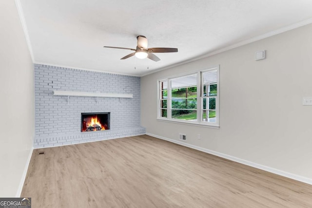 unfurnished living room with light wood-type flooring, a brick fireplace, and ornamental molding