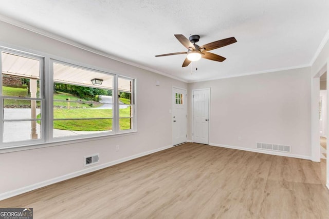 empty room with a textured ceiling, ceiling fan, light wood-type flooring, and crown molding