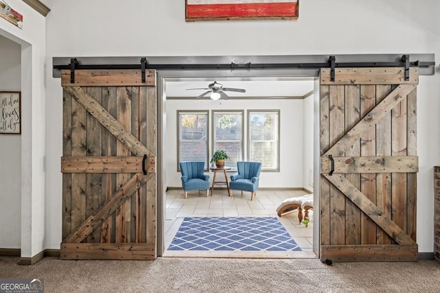 interior space featuring a barn door, carpet floors, and ceiling fan