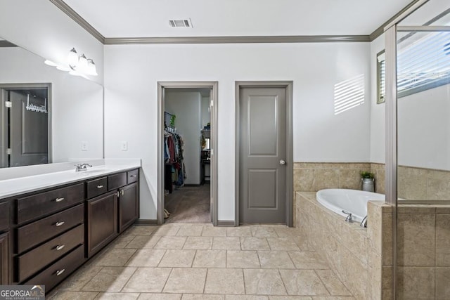 bathroom with vanity, ornamental molding, and tiled tub