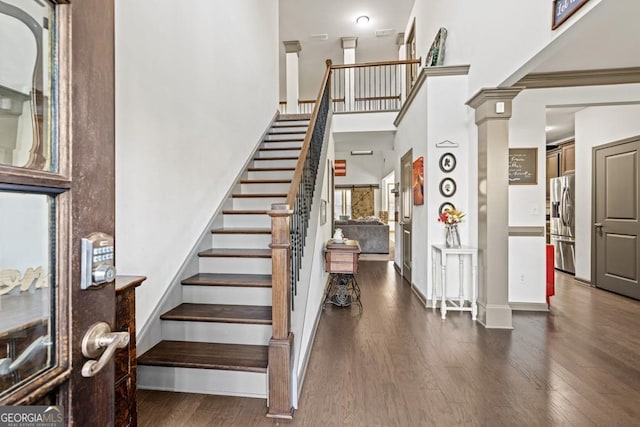 stairway with ornate columns, crown molding, and hardwood / wood-style flooring