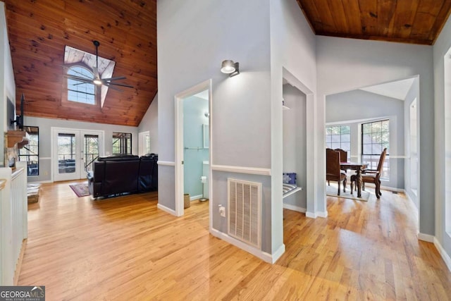 hallway featuring light hardwood / wood-style flooring, high vaulted ceiling, and a healthy amount of sunlight