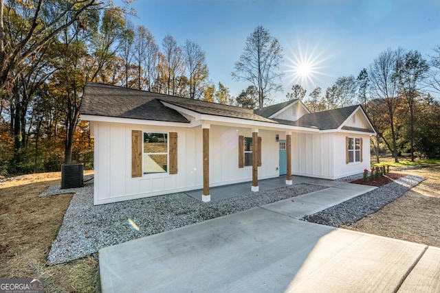 view of front of home featuring board and batten siding, roof with shingles, a porch, and central air condition unit