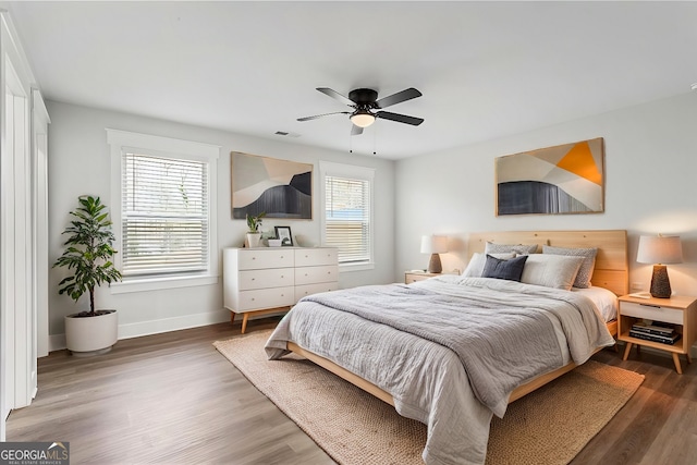 bedroom with ceiling fan, dark wood-style flooring, visible vents, and baseboards