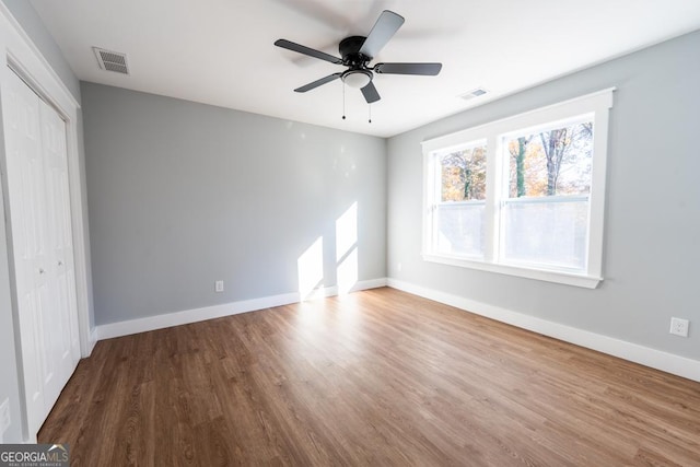 unfurnished bedroom with baseboards, a closet, visible vents, and wood finished floors