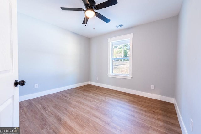 empty room with light wood-style floors, baseboards, visible vents, and a ceiling fan