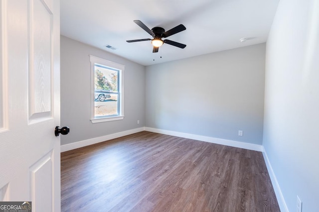 empty room with ceiling fan, wood finished floors, visible vents, and baseboards