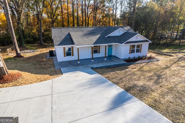 modern inspired farmhouse featuring driveway, central AC unit, and roof with shingles