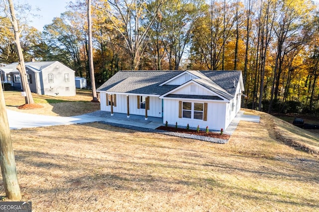 view of front of property with a porch, a front yard, and a shingled roof