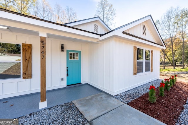 doorway to property with board and batten siding and a porch