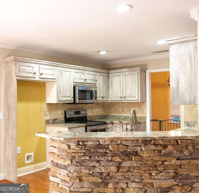 kitchen with light stone countertops, sink, stainless steel appliances, backsplash, and light wood-type flooring